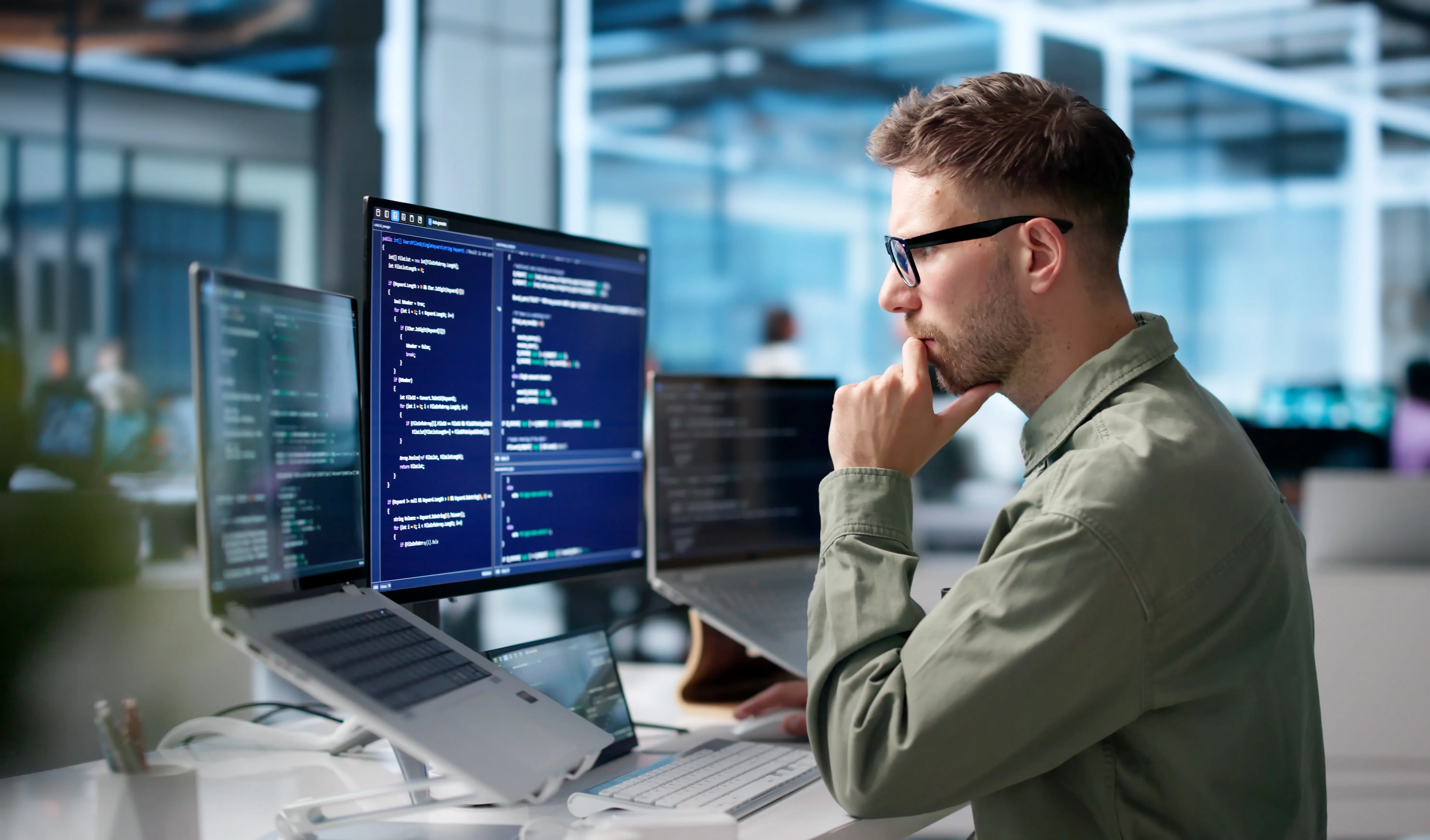 Employee reviewing code on multiple screens, highlighting AI literacy in the workplace.
